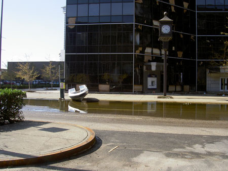 Random boat washed up in front of commercial glass building